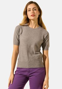 Pull en tricot gris clair à manches courtes avec un col rond, texture douce, design ajusté, associé à un pantalon violet pour un contraste.