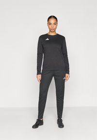 Μαύρο αθλητικό σετ με φούτερ και παντελόνι από λείο ύφασμα, με λευκές λεπτομέρειες λογότυπου Adidas και στα δύο κομμάτια.