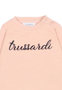 T-shirt rose doux avec col rond, arborant un logo "trussardi" brodé en marine et deux pressions sur les épaules pour un enfilage facile.