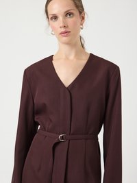 Μπορντό φόρεμα σακάκι με βαθύ V-λαιμόκοψη και μακριά μανίκια, με υφασμάτινη ζώνη με στρογγυλή μεταλλική αγκράφα, στενή εφαρμογή και ομαλή υφή.