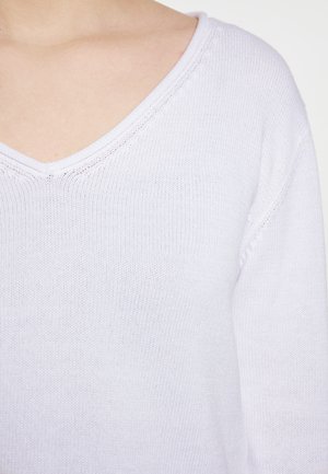 Lys lilla V-hals sweater med en fin strikket tekstur, der har ribbede kanter langs halsudskæringen og manchetterne.
