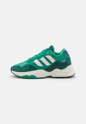 Green suede and mesh sneaker with white and purple accents. Features three white stripes and a thick white sole with textured green outsole.