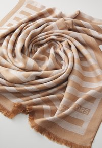 Écharpe tissée beige et tan avec des motifs de rayures horizontales et verticales, des bords frangés et une texture douce.