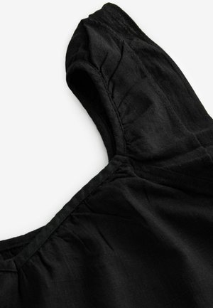 Sort linnedragt med rund halsudskæring, korte ærmer og samlede detaljer ved skuldrene og brystet. Glat tekstur, let materiale.