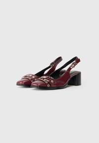 Tacchi slingback in pelle bordeaux con punta affilata, dotati di hardware decorativo in argento e una tracolla texturizzata. Design con tacco basso a blocco.