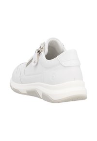 Basket en cuir blanc avec fermeture éclair, semelle rembourrée et texture lisse. Comprend un logo discret sur le côté et le talon.