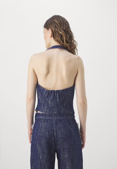 Denim halter-top med åpen rygg, har en samlet tekstur og mørkeblå farge, parret med matchende high-waisted bukser.
