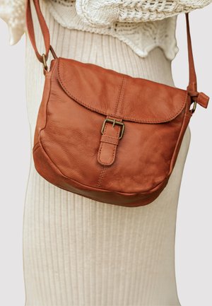 Ruda odinė per petį nešama tašė su sklendžio uždarymu, reguliuojamu dirželiu ir priekiniais sagties akcentais. Minkšta tekstūra ir apvalios formos.