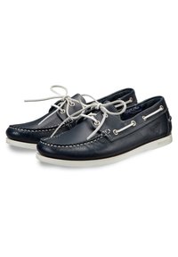 Scarpe da marinaio in pelle blu navy con suole in gomma bianche, caratterizzate da cuciture a contrasto, chiusura con lacci e occhielli in metallo.