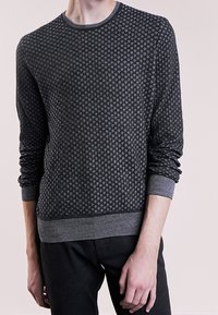 Pull en maille gris foncé avec un motif en losanges texturé, col rond et poignets et ourlet côtelés. Le matériau semble doux et léger.