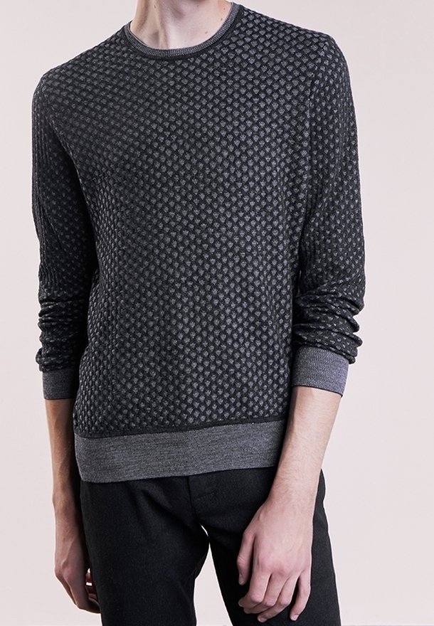 Pull en maille gris foncé avec un motif en losanges texturé, col rond et poignets et ourlet côtelés. Le matériau semble doux et léger.