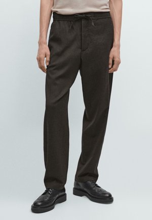 Dunkelbraune Hose aus strukturiertem Stoff, mit einem Kordelzugbund, geradem Schnitt und Seitentaschen, kombiniert mit schwarzen Schnürschuhen.
