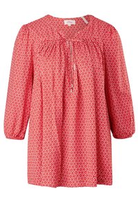 Blouse rouge avec motif géométrique blanc, détails froncés au niveau de l'encolure et manches bouffantes trois-quarts, fabriquée en tissu léger.