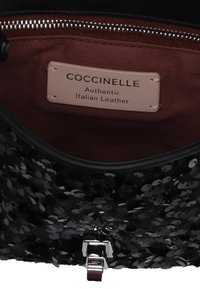 Borsa nera decorata con paillettes, con una superficie testurizzata, dotata di un ferma conchiglia in metallo e un interno foderato. L'etichetta riporta "COCCINELLE Autentica Pelle Italiana."
