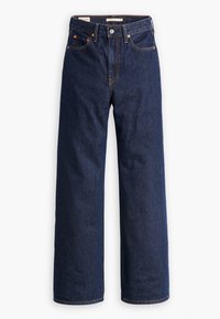 Jean large en denim foncé, doté de cinq poches, de coutures orange et d'une fermeture à boutons. Le tissu a une texture lisse.