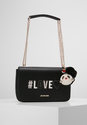 Sort Moschino håndtaske med gylden kæderem, teksten "#LOVE", hjertesymbol og en dekorativ nøglering med ansigt med røde læber og sort pompom.