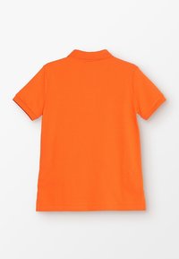 Kortärmad polo i stark orange. Tillverkad av mjuk bomull med klassisk krage. Har en ren finish utan synliga mönster.