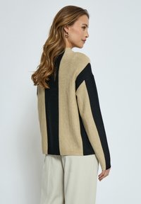 Beige und schwarzer gestreifter Pullover mit lockerer Passform. Aus weichem Stoff gefertigt, mit langen Ärmeln und rundem Halsausschnitt.