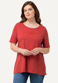 Camiseta roja de manga corta con cuello redondo y la palabra "PURE" escrita en un diseño contrastante, hecha de una tela suave y ligera.