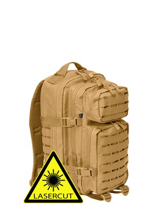 Beżowy plecak taktyczny z wieloma zamykanymi kieszeniami i panelami wentylacyjnymi wycinanymi laserowo, pokazany z żółtym laserowo wycinanym znakiem ostrzegawczym.