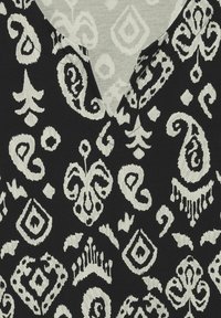Schwarzer Stoff mit komplizierten weißen Paisleymustern und einer strukturierten Oberfläche sowie einem V-Ausschnitt.