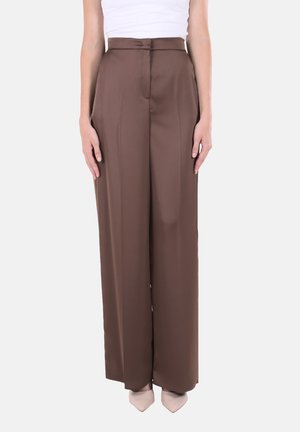 Pantaloni marroni a vita alta con gamba larga, pieghe anteriori e consistenza liscia. Abbinati a scarpe color chiaro con punta affusolata.
