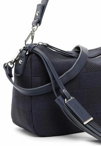 Granatowa torebka wykonana z fakturowanej tkaniny z gładkimi skórzanymi akcentami. Posiada zamek błyskawiczny oraz odpinany pasek na ramię z metalowymi detalami.