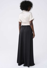 Lichtbeige top met korte mouwen, gecombineerd met zwarte hoge taille brede broek, gemaakt van een zachte stof met een elastische tailleband.
