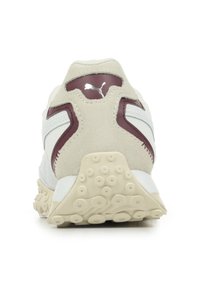 Sneaker bianca e beige con un tallone in suede testurizzato, accenti bordeaux e una suola in gomma decorata con punti di grip circolari.