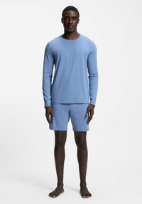 Blue long-sleeve top and matching shorts made of soft fabric, featuring a minimal logo on the chest. The outfit is lightweight and breathable.