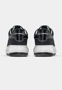 Crne tenisice od brušene kože s crnim sjajnim panelom na peti i bijelim potplatom. Imaju logo na peti, okrugli dizajn i teksturiranu površinu.