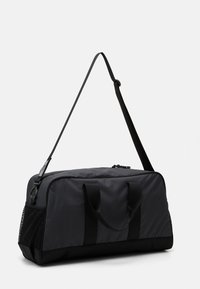 Black nylon duffel bag with a rectangular shape, featuring dual top handles, an adjustable shoulder strap, and a mesh side pocket.