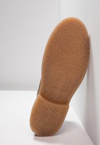 Hnědá guma podrážky boty s texturovaným, protiskluzovým povrchem. Na oblasti paty se nachází embosované logo "JACK & JONES".