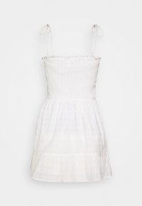 Bílé šaty s nastavitelnými špagetovými ramínky, smíšeným živůtkem a rozšířenou sukní s jemnou krémovou texturou a volánkovým lemem.