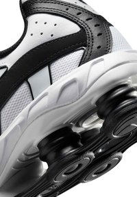 Λευκή και μαύρη σόλα αθλητικού παπουτσιού με ορατά ελατηριοειδή μαξιλαράκια απορρόφησης κραδασμών και στήριξης.