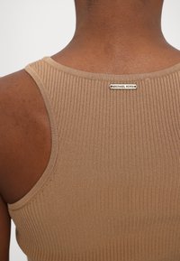 Brown ribbed tank top featuring a round neckline and an embossed metal Michael Kors logo on the back. Smooth texture and fitted design.