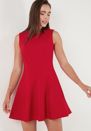Red sleeveless dress with a flared skirt, made of smooth fabric. Features vertical seams and a fitted bodice, creating a structured silhouette.