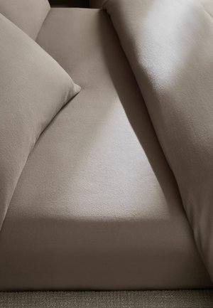 Beiges Stoffsofa mit zwei Kissen und sichtbarem Sitzbereich unter weichem natürlichem Licht.