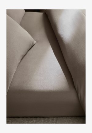 Beiges Stoffsofa mit zwei Kissen und sichtbarem Sitzbereich unter weichem natürlichem Licht.
