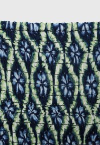 Patterned fabric featuring a floral design in blue and green hues with a textured, quilted surface and dark navy accents.