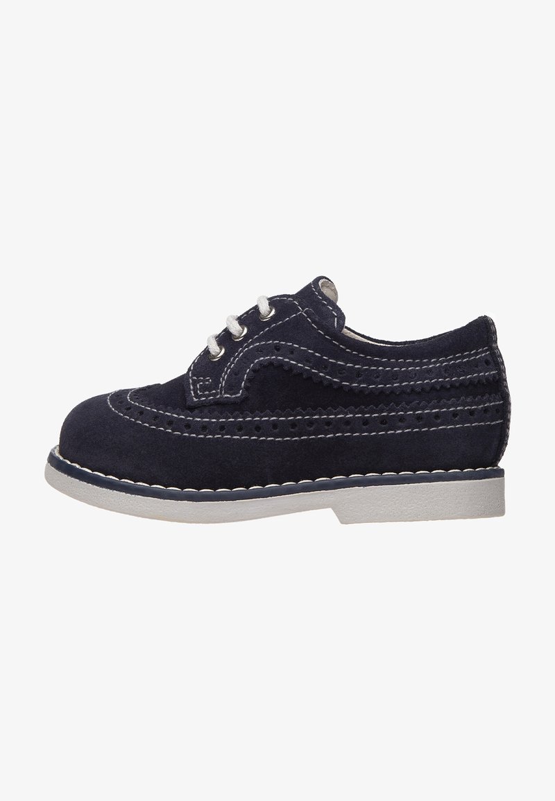 Chaussure oxford enfant à bouts fleuris en daim bleu foncé avec surpiqûres blanches, lacets blancs et semelle en caoutchouc gris clair, vue de côté.