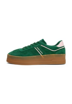 Grüner Veloursledersneaker mit dicker brauner Sohle, rosa Akzenten, Schnürung vorne und „Tommy Jeans“-Label auf dem seitlichen Panel.
