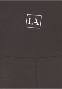 Zwarte sportkledingstof met een wit vierkant logo met de letters "LA". Vlotte textuur met een aansluitend ontwerp. Geen andere opmerkelijke details.