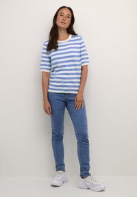 Randig t-shirt i ljusblått och vitt, kortärmad, rund hals. Matchad med blå skinny jeans och vita sneakers. Minimalistisk design.