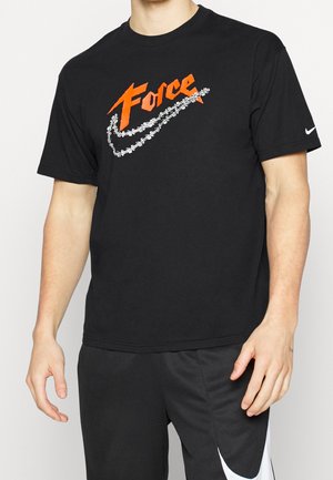 Homme portant un t-shirt noir avec le texte orange « Force » et un swoosh Nike à motif chaîne, associé à un short noir avec un grand swoosh blanc.