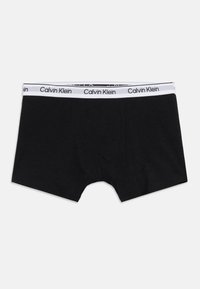 Μαύρα αντρικά μποξεράκια με λευκή ελαστική μέση που φέρει το λογότυπο Calvin Klein με μαύρο κείμενο.