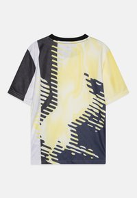 T-shirt à manches courtes avec un design graphique en jaune, noir et blanc. Pr�ésente une texture en maille et des motifs abstraits de différentes épaisseurs.