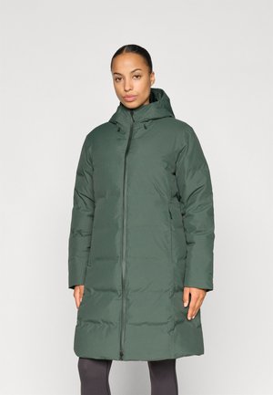 Zelená vypchátá bunda s kapucňou, ktorá má predný zips a bočné vrecká. Hladká textúra a dĺžka po kolená.