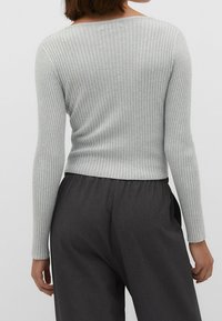 Grau geripptes Langarmoberteil mit U-Boot-Ausschnitt, eng anliegenden Ärmeln und gekürztem Saum, getragen zu dunkelgrauen Hosen.