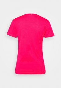 Camiseta rosa de manga corta, con un escote redondo y una textura suave. La parte trasera presenta un pequeño acento vertical en el cuello.